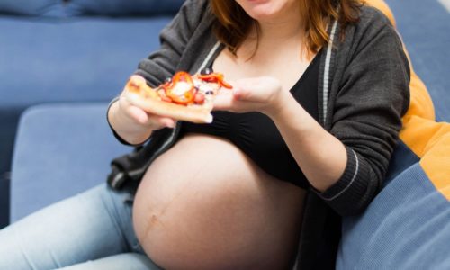 Pregnant woman eating pizza